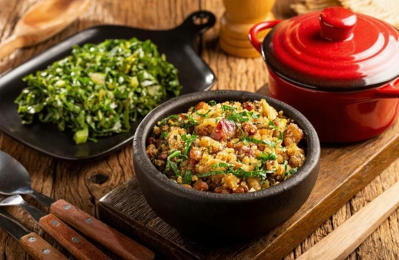 Feijão tropeiro servido em prato de barro, com arroz branco, couve refogada e torresmo, representando a culinária tradicional brasileira.