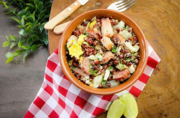Prato típico brasileiro de feijão tropeiro servido em uma tigela de barro, acompanhado de arroz branco, couve refogada e torresmo crocante.