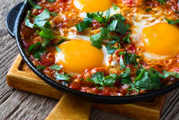 Receita com ovo e molho de tomate servida em panela de ferro fundido. 