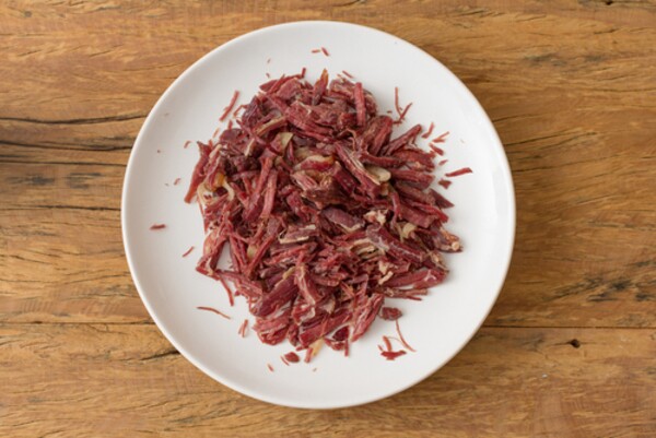 Prato de cerâmica com carne seca em mesa de madeira