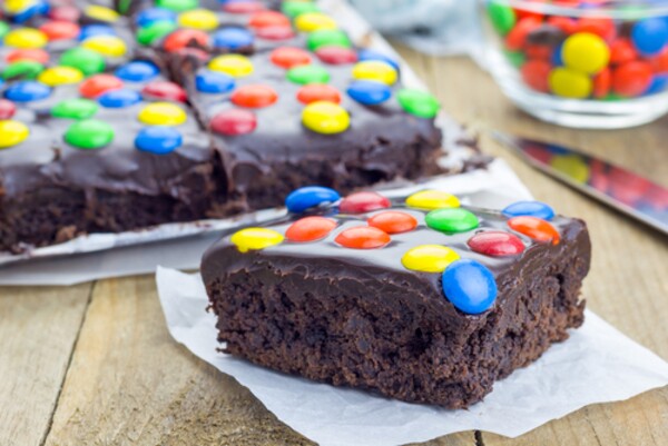 Brownie com calda de chocolate e gotas de chocolate coloridas.