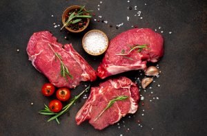 Diferentes tipos de carne bovina crus cortados com especiarias em placa de corte.
