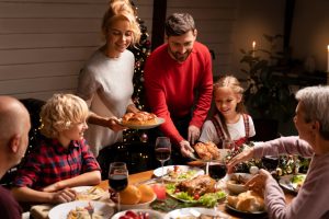 Família reunida ao redor da mesa celebrando um jantar festivo, com pratos variados e decoração acolhedora, representando união e momentos especiais em grupo.