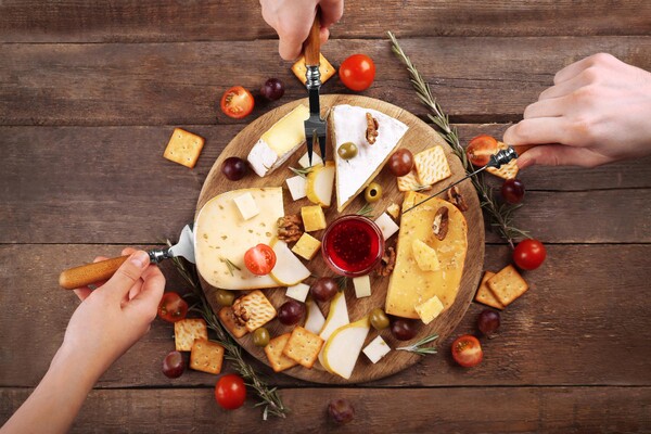 Grupo de mulheres se divertindo enquanto saboreiam diferentes petiscos e vinho, sentadas ao redor de uma mesa em ambiente acolhedor, representando momentos de confraternização e amizade.