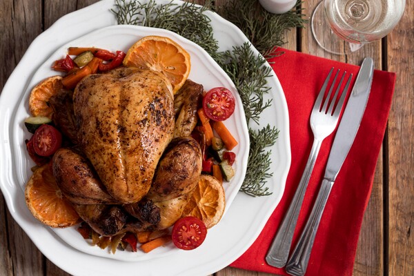 Peru assado recheado acompanhado de maçãs assadas, servido em uma travessa decorada com ervas frescas, representando um prato festivo e sofisticado ideal para ocasiões especiais.