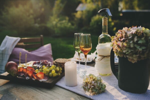 Uma tábua de frios gourmet servida com queijo, presunto, frutas frescas como uvas e morangos, disposta elegantemente sobre uma bandeja de madeira.