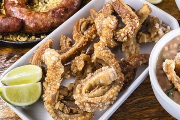 Prato típico da culinária mineira com variedade de alimentos regionais servidos em travessas de barro, incluindo arroz, feijão, couve, torresmo e farofa. 